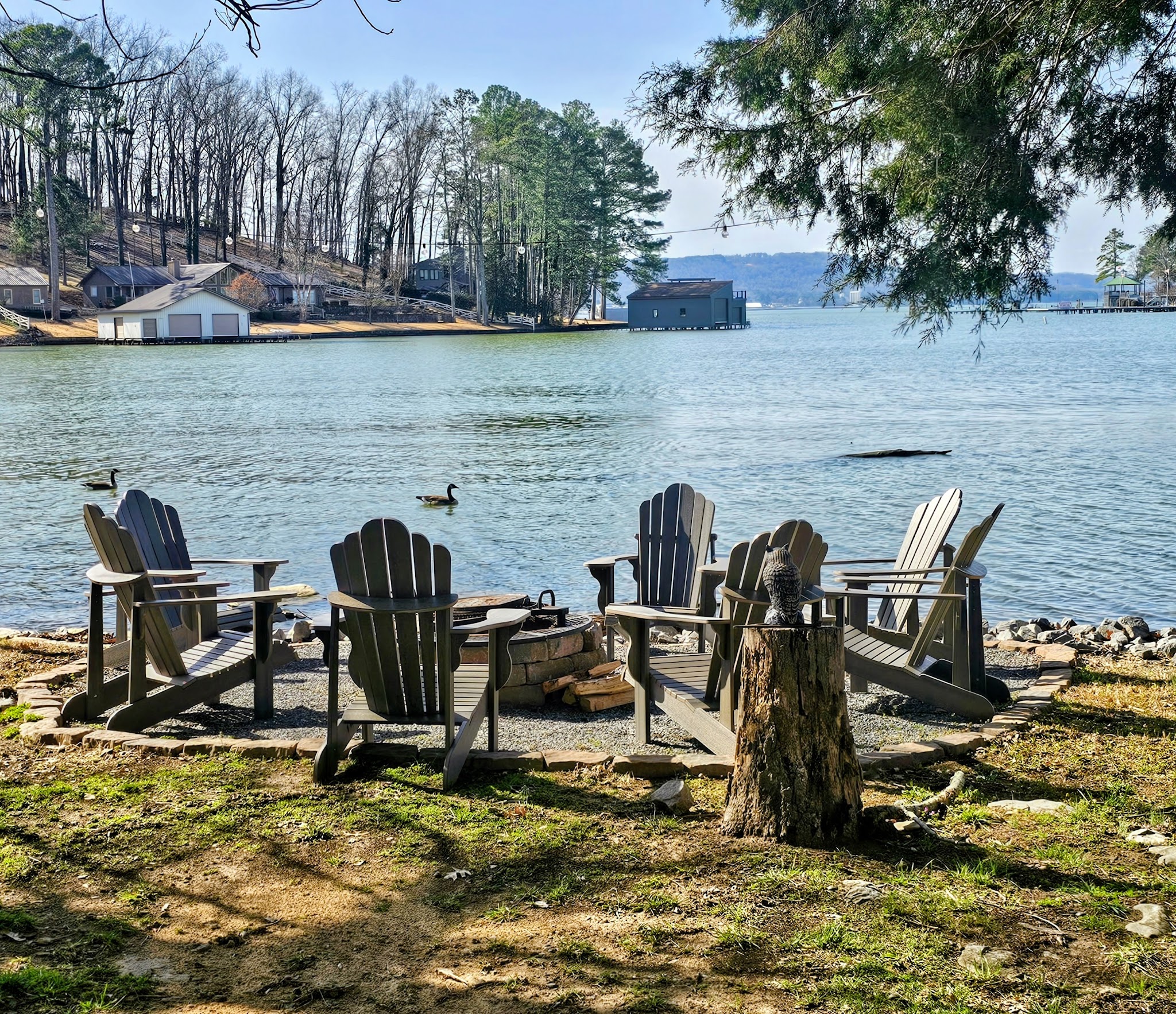 Adirondack chairs on the flat lakefront yard for family downtime at Guntersville Getaway