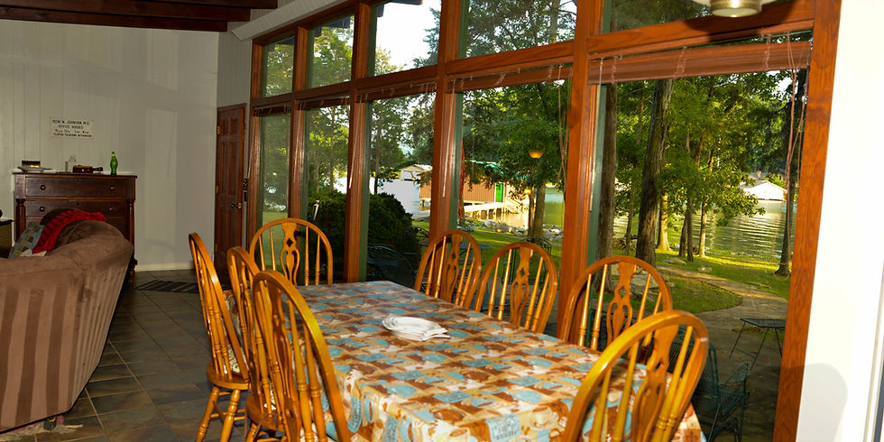 Dining area with floor-to-ceiling lake view windows overlooking the yard and cove at Guntersville Getaway